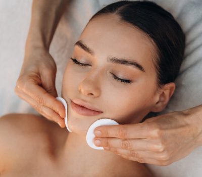Cleaning the face skin. Relaxed young woman getting massage by therapist in spa salon.