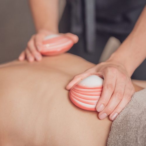 A closeup shot of the masseur's hands massaging her client's back with lava shells.