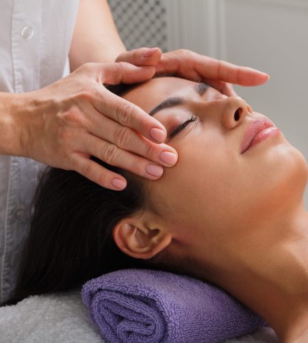 Massagist with woman patient in aroma spa wellness center. Professional face lifting massage to beautiful girl in cosmetology cabinet or beauty parlor.